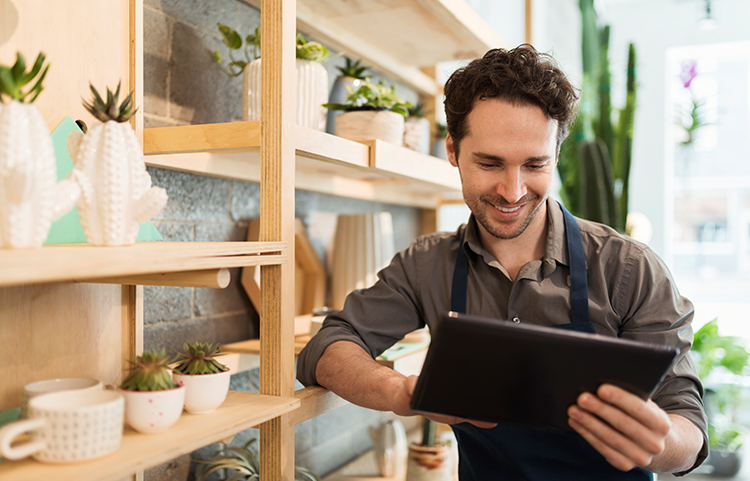 Le propriétaire d'une petite entreprise regarde et sourit en regardant ce qu'il lit sur une tablette